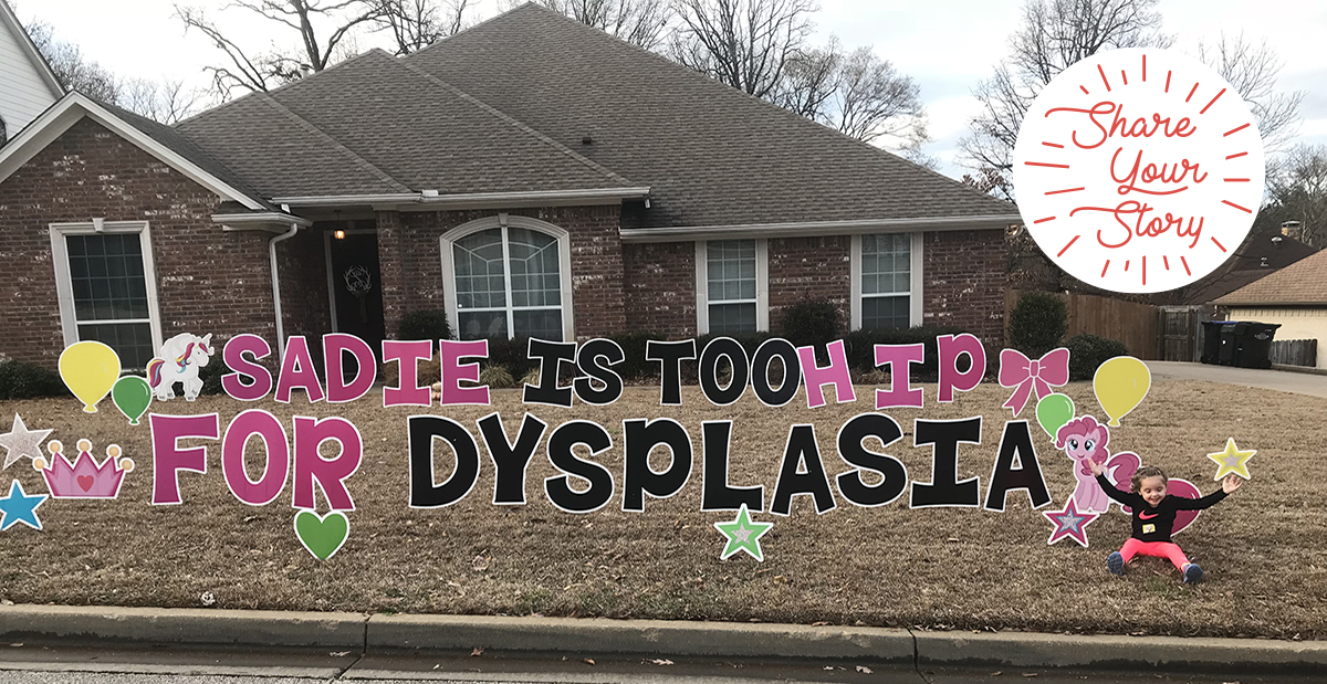 sadie with yard sign in front of house